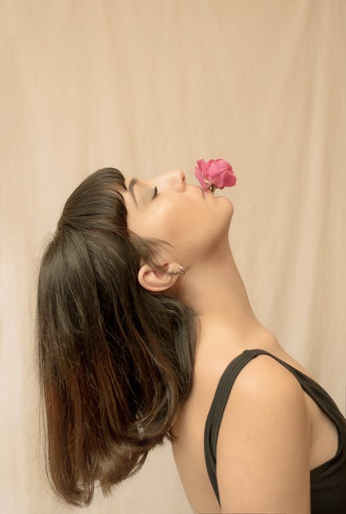 黑色背心与耳朵上的粉红玫瑰的女人 · 免费素材图片