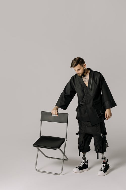 黑色皮夹克站立和拿着椅子的人 · 免费素材图片