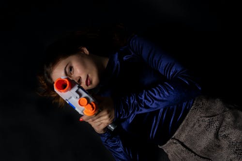 女人穿着蓝色的长袖衬衫，拿着nerf枪 · 免费素材图片