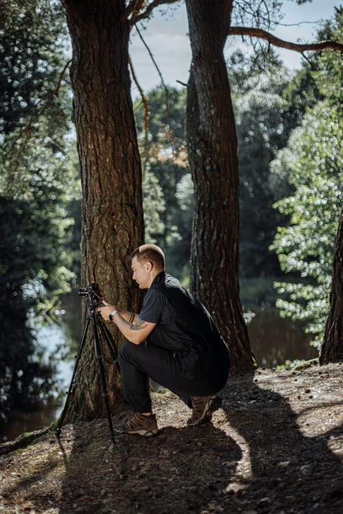 黑色外套和棕色的帽子，坐在树干上的男人 · 免费素材图片