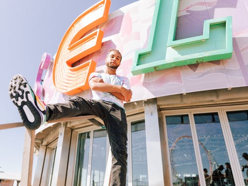 男子在折叠手臂时将右腿搁在扶手上 · 免费素材图片