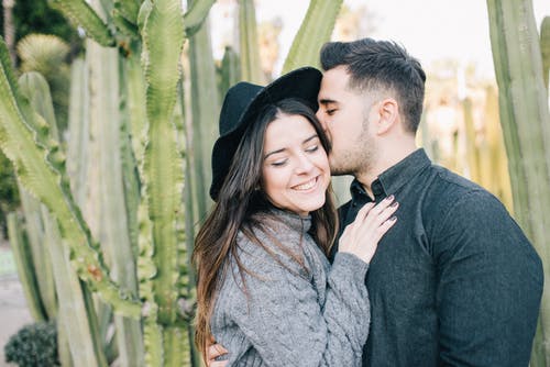 黑帽子的男人亲吻女人的灰色毛衣 · 免费素材图片