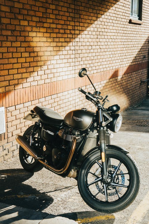一辆摩托车停在砖墙附近 · 免费素材图片