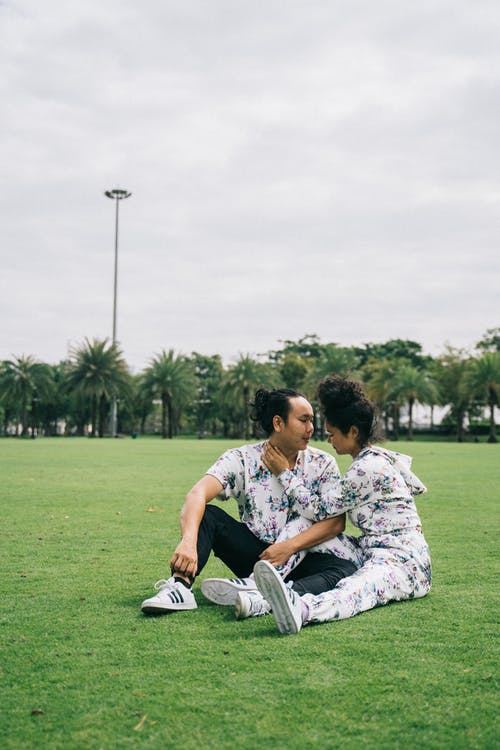 男人和女人坐在绿草地上 · 免费素材图片