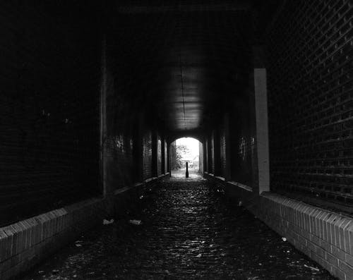 在隧道上行走的人的灰度照片 · 免费素材图片