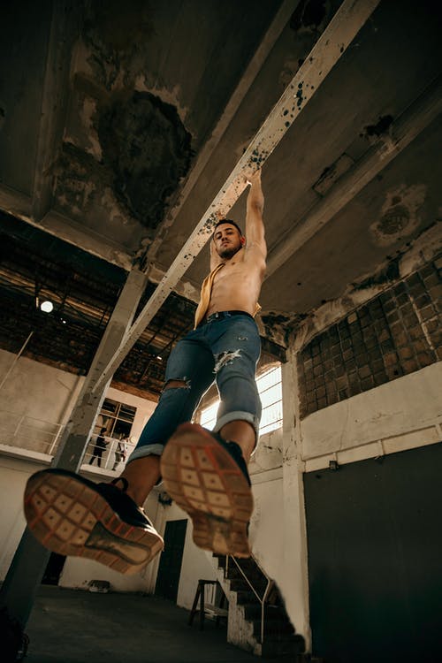 男子穿着破牛仔裤坚持杆半空中 · 免费素材图片
