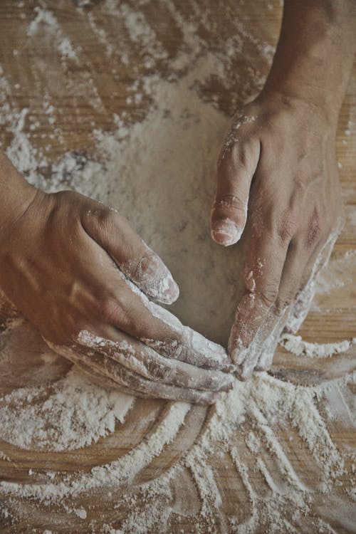 拿着白色粉末在棕色木桌上的人 · 免费素材图片