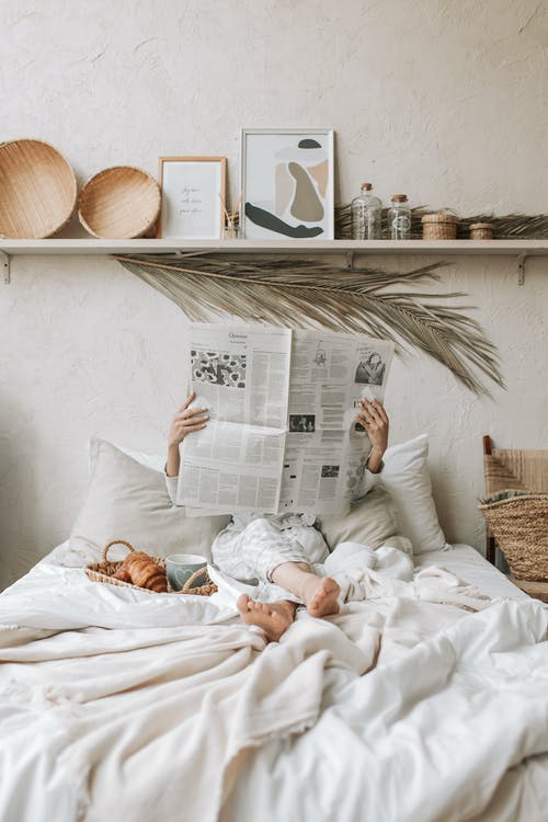 躺在床上看报纸的灰色长袖衬衫的女人 · 免费素材图片
