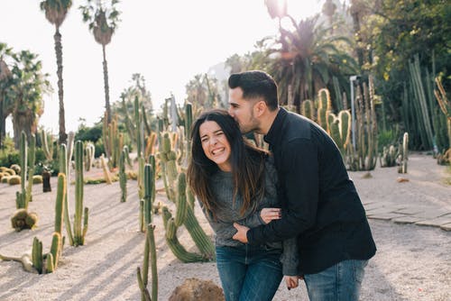 黑夹克的男人拥抱绿色和黑色的条纹的长袖衬衫的女人 · 免费素材图片