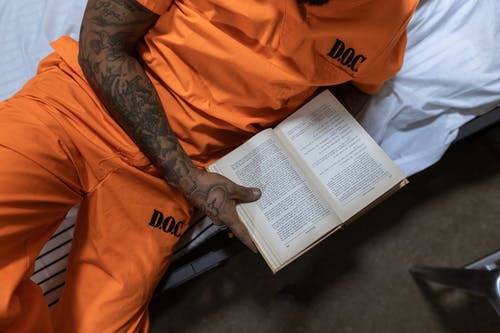 橙色衬衫阅读书中的人 · 免费素材图片