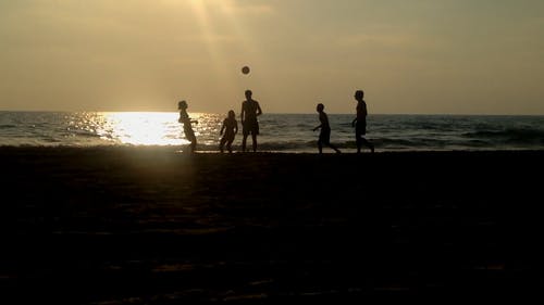 在日落期间在沙滩上打踢球 · 免费素材视频