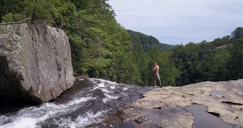 人站在瀑布附近的悬崖上 · 免费素材视频