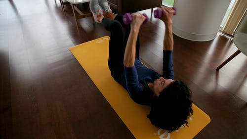 一个女人在客厅地板上的瑜伽垫上锻炼的慢动作镜头 · 免费素材视频