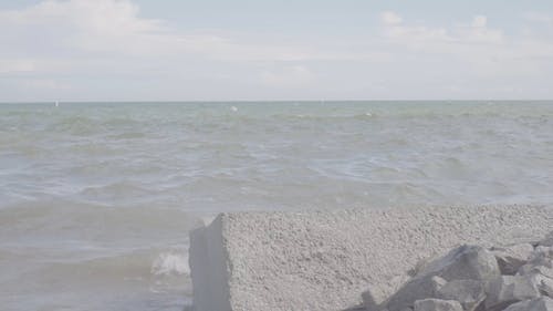 海浪在岩石和混凝土屏障上破碎的低角度镜头 · 免费素材视频