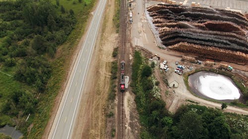 空中的镜头，在慢速行驶的火车穿过木材场 · 免费素材视频