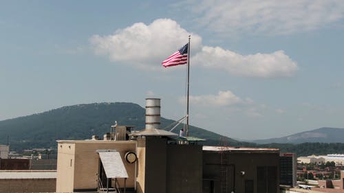 从建筑物顶部的杆子上撤出美国国旗 · 免费素材视频
