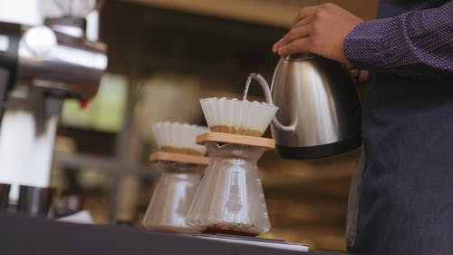 将热水倒在装满咖啡粉的过滤器上以制成冲泡咖啡 · 免费素材视频