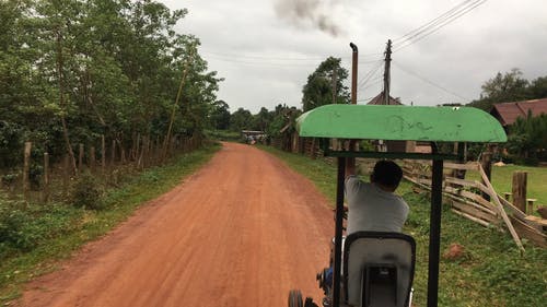 一辆小型车辆在农村地区未铺砌的道路上行驶的跟踪镜头 · 免费素材视频