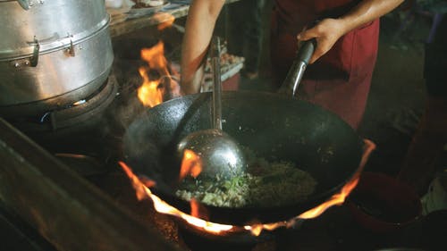 一个人在高火炉上的锅中熟练地混合炒饭的慢动作镜头 · 免费素材视频