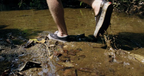 一个穿着橡胶鞋在浅河里行走的人 · 免费素材视频