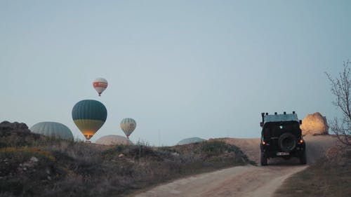 一辆四轮驱动越野车在崎di的土路上行驶，朝着热气球的起飞地点行驶 · 免费素材视频