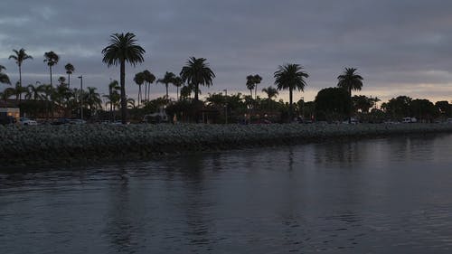 一条河的寂静水流，人们在黄昏时分在社区两岸漫步 · 免费素材视频