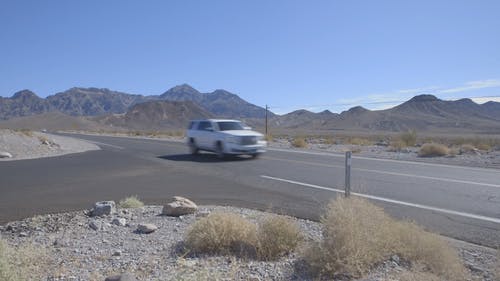 一个女孩在白天的山景为低交通沙漠路拍照 · 免费素材视频