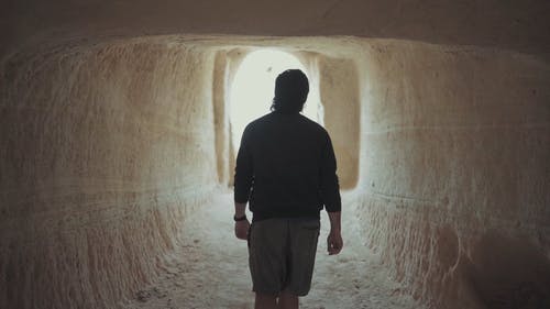 一个男人走出一个男人雕刻的古老洞穴的背面 · 免费素材视频