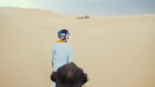 一个本地人沿着他的骆驼拖到一群人在沙漠中的慢动作镜头 · 免费素材视频