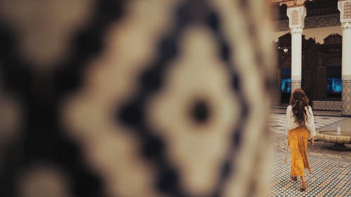 一个女人走在有美丽的马赛克瓷砖地板和列的庭院里的慢动作镜头 · 免费素材视频