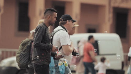 男子在大街上卖肥皂泡泡水枪 · 免费素材视频