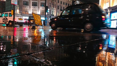 人行道上湿路面的低天使镜头与一个标牌在城市的一个雨夜 · 免费素材视频