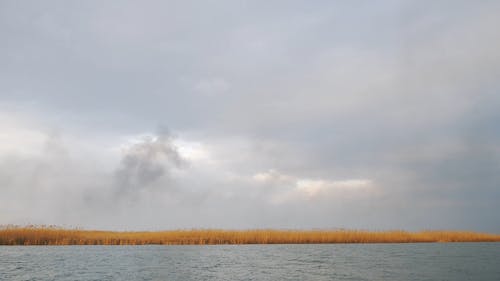 时间流逝的镜头，云形成在橙色的田野和河 · 免费素材视频