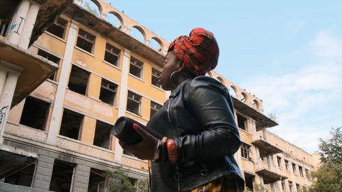 皮夹克的女人环顾四周废弃的建筑物 · 免费素材视频