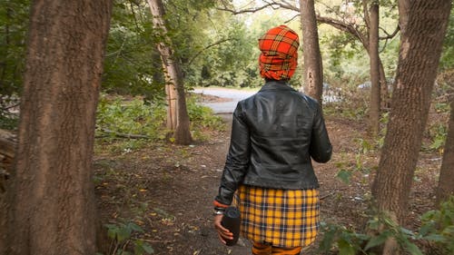 一个女人走出树林往路的背面 · 免费素材视频