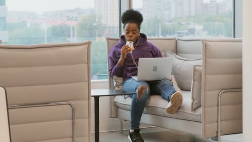 一个女人坐在舒适的笔记本电脑上吃糖果的酒吧 · 免费素材视频