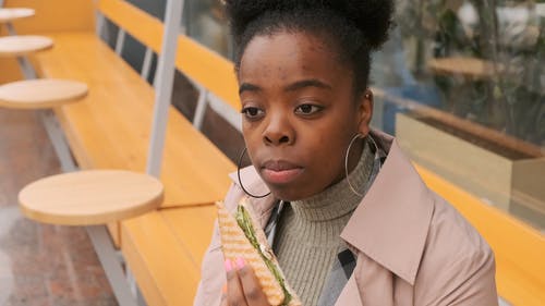 一个女人在咖啡厅的室外座位上吃三明治和咖啡的小吃 · 免费素材视频