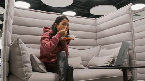 一个女人一边吃一边在笔记本电脑上工作 · 免费素材视频