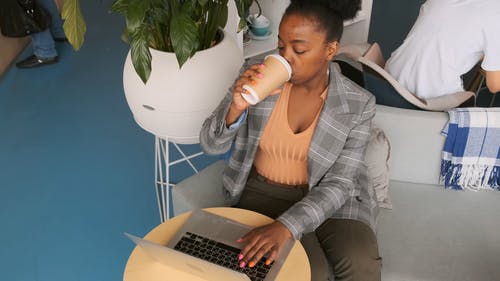 一个女人在她的笔记本电脑上工作时喝一杯咖啡 · 免费素材视频