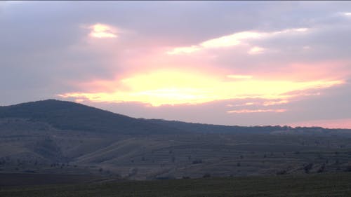 时间流逝的镜头覆盖云层覆盖广阔的绿色土地和一座山上的太阳 · 免费素材视频