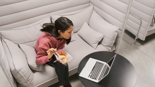 一个女人在笔记本电脑上工作时吃她的食物 · 免费素材视频