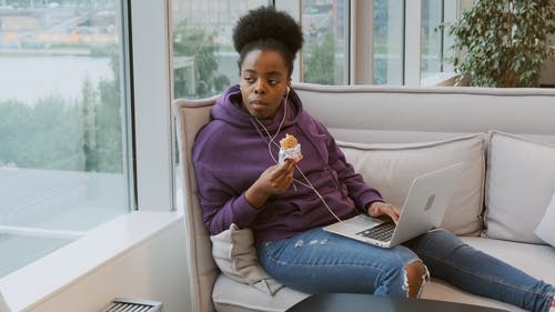 一个坐在她的膝上有笔记本电脑时吃糖果的女人 · 免费素材视频
