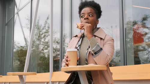 一个女人在户外的咖啡厅吃她的三明治和咖啡 · 免费素材视频