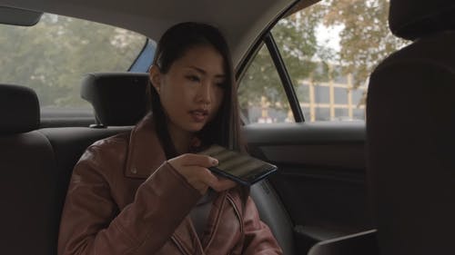 在与她的笔记本电脑和手机一起工作的汽车后座的女人 · 免费素材视频
