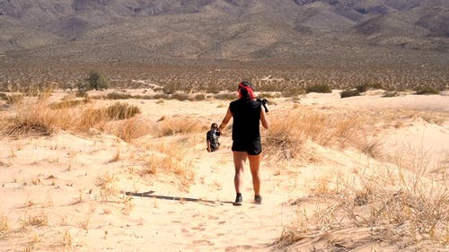 两人用相机在白天在山丘和山脚下的沙质沙漠地上拍照 · 免费素材视频