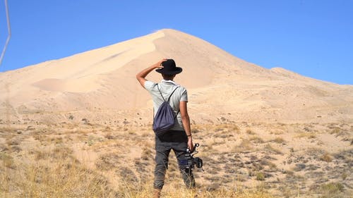 拿着照相机的一个人的后面观点站立在点心的沙丘前面 · 免费素材视频