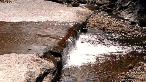 一条窄浅的河水流过岩石床 · 免费素材视频