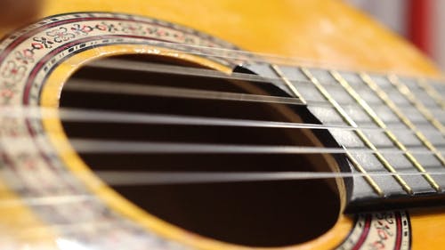 一把黄色吉他的特写镜头，其弦从吉他手的弹跳中振动 · 免费素材视频