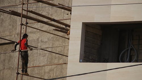建筑工人在通过建筑材料的钢脚手架上保持平衡的低角度镜头 · 免费素材视频