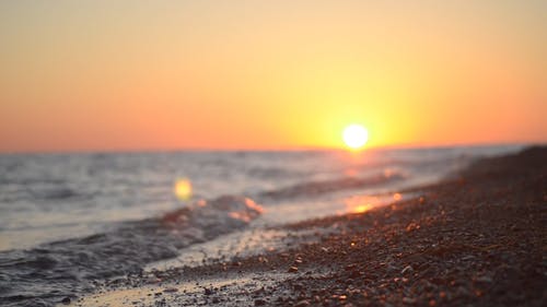 地平线上落日的海浪冲破岸边的地面镜头 · 免费素材视频